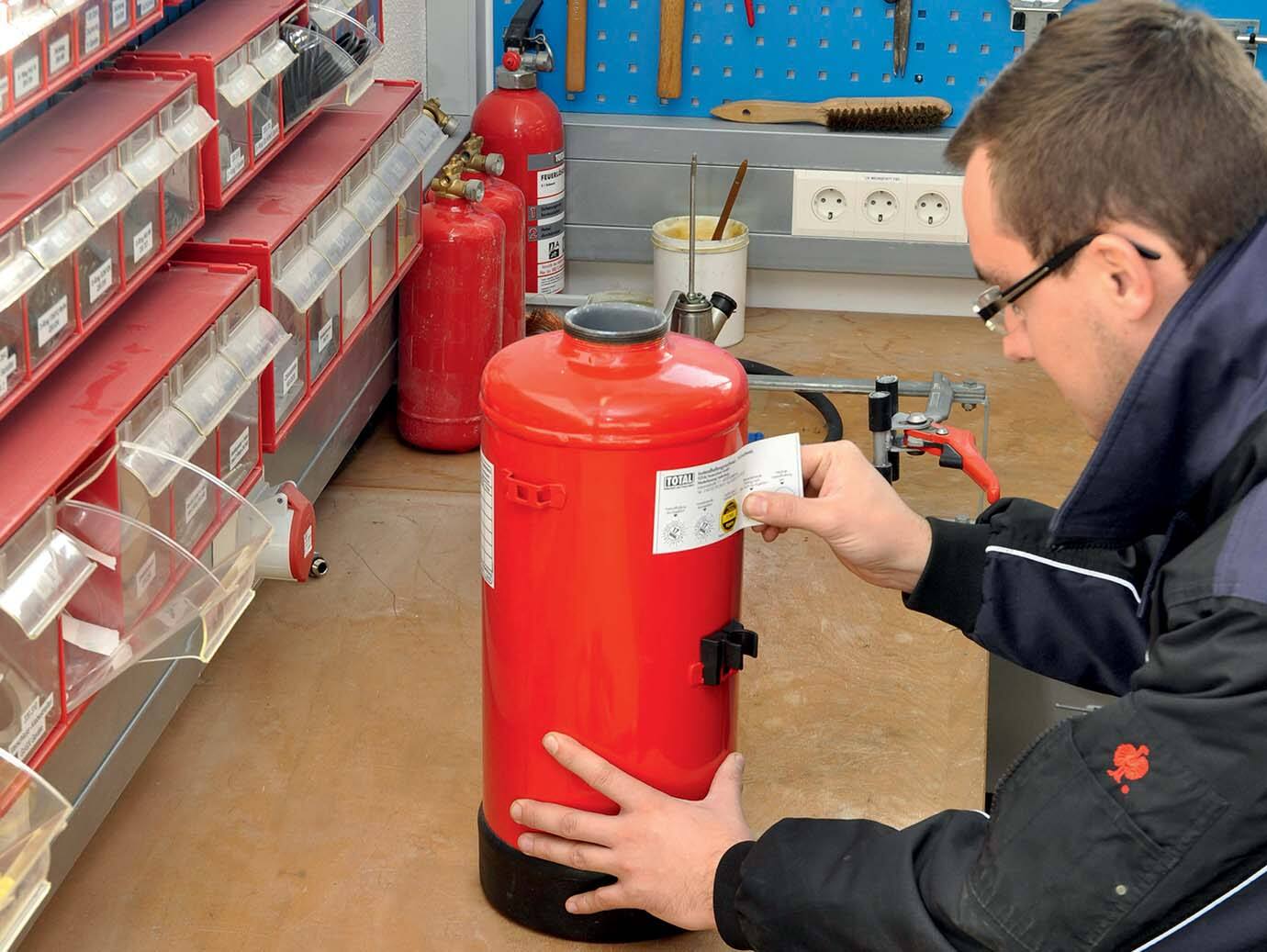Firefighter pasting a label on a fire extinguisher