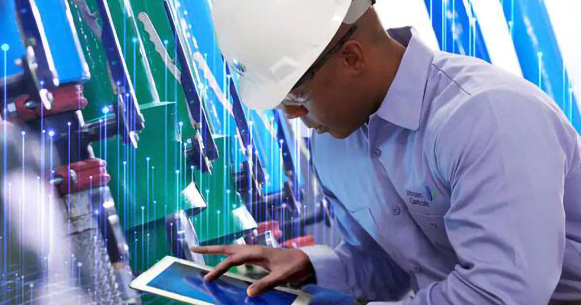 A man in a Johnson Controls safety helmet operating a tablet overlaid with graphics of transmission nodes