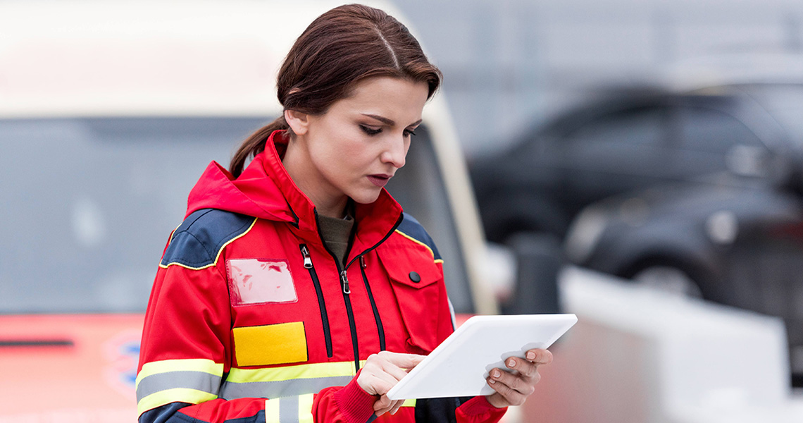 A paramedic working on a tablet in front of an ambulance
