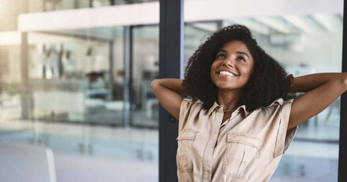 Young woman smiling and stretching her arms in an office