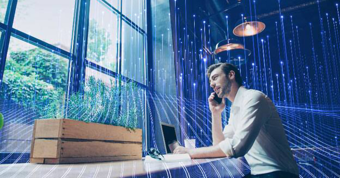 Man working at his desk in office, overlaid with a graphic of transmission nodes